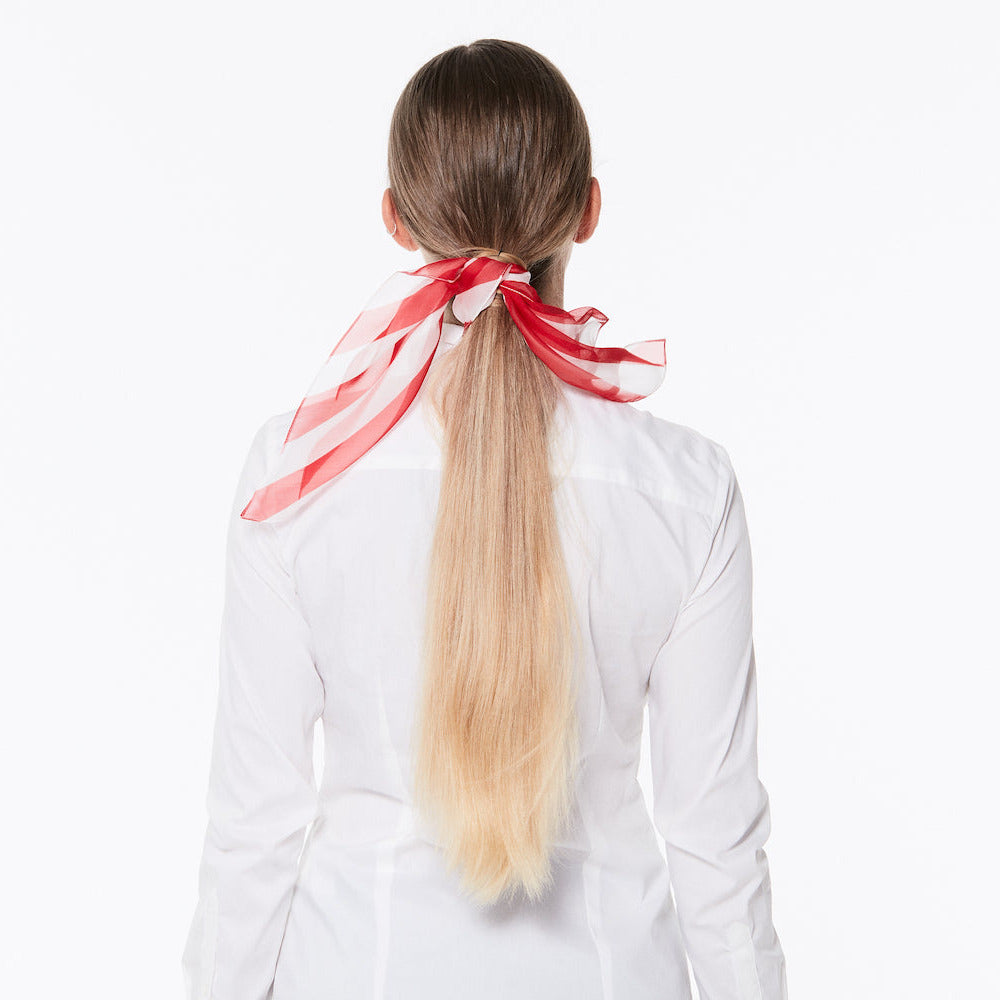 Maria wearing with a ponytail wearing a silk scarf race leader on a white background