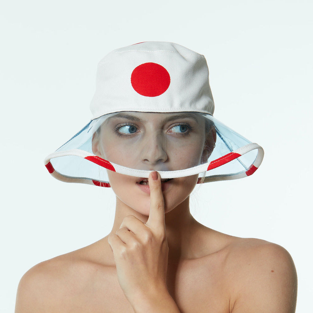 Maria wearing a white bucket hat with a red dot on a white background