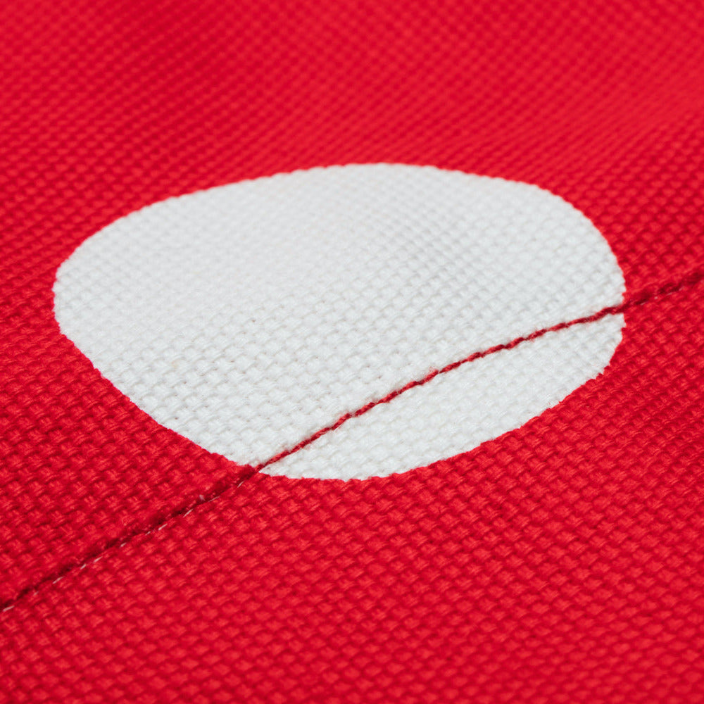 Close-up of a red fabric with a white dot and stitching detail.